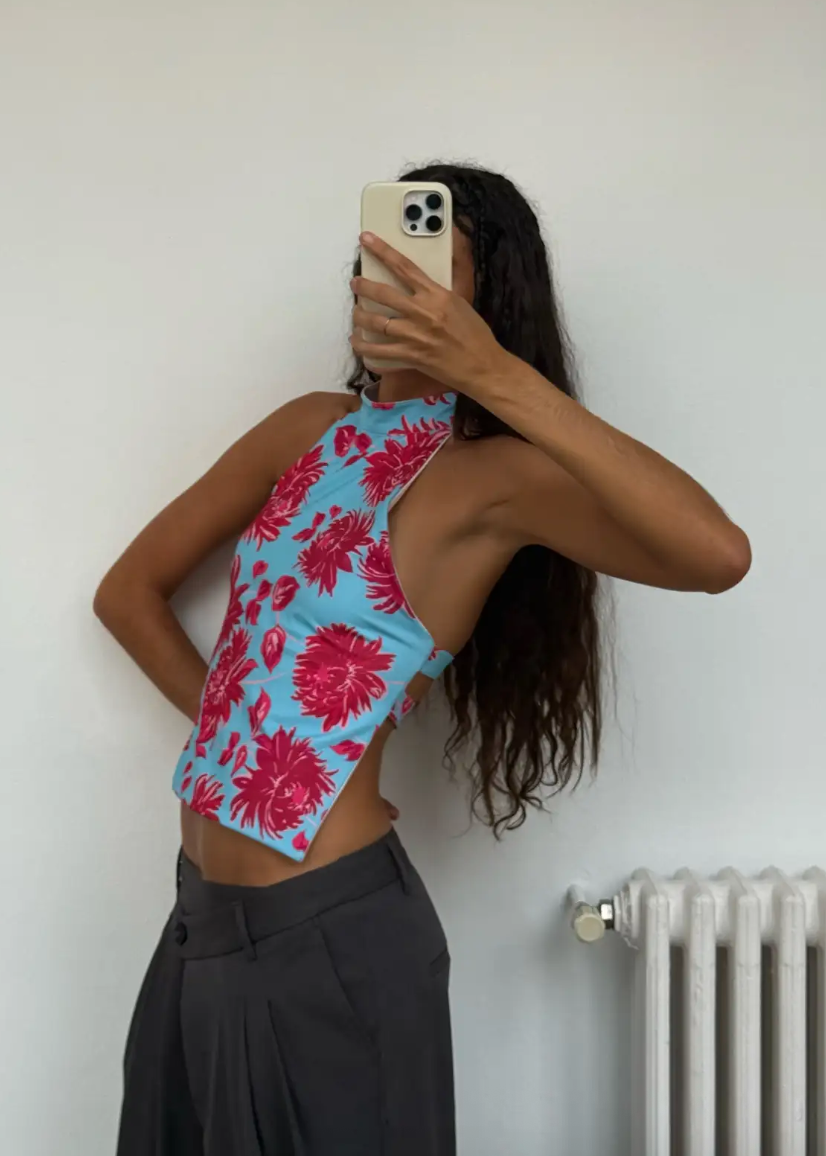 Person wearing a blue and pink floral top taking a mirror selfie.