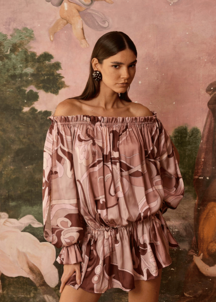 Woman in a patterned dress standing in front of an classical painting