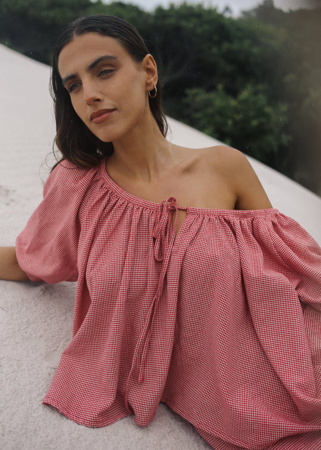 Woman wearing a pink off-shoulder top with a blurred natural background