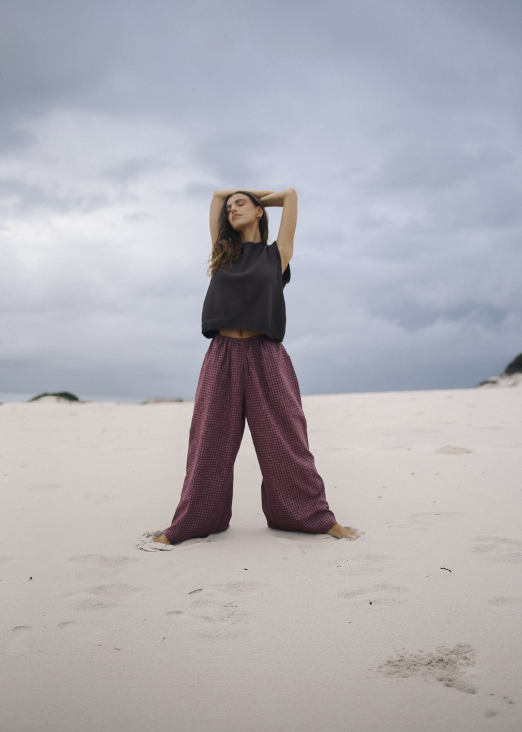 Person standing on a sandy dune with a cloudy sky