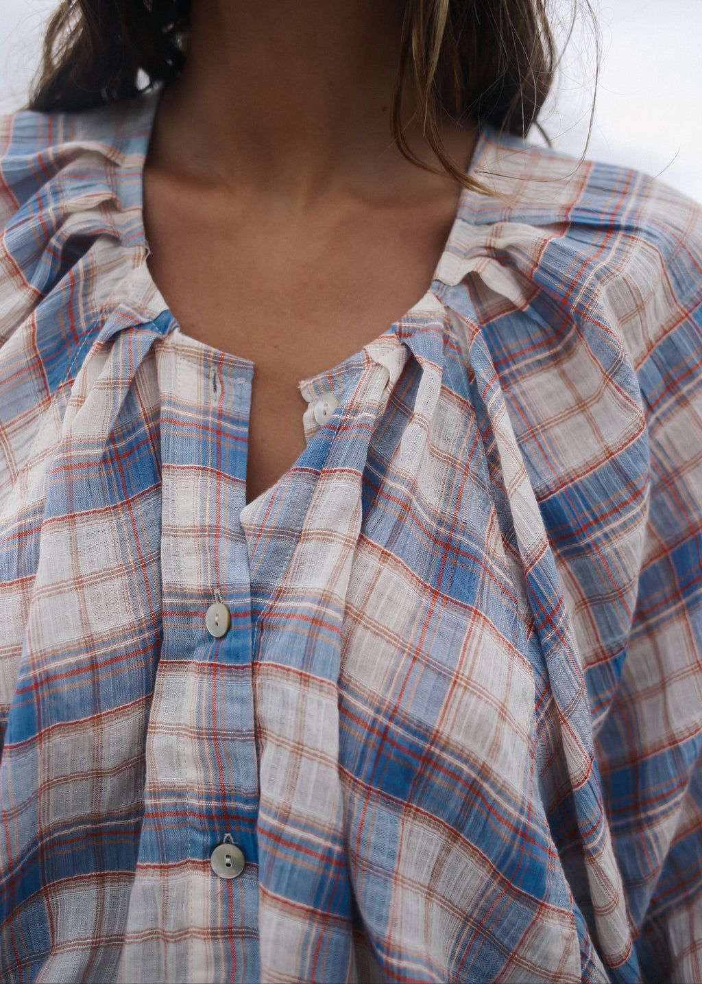 Close-up of a person wearing a plaid shirt with a neutral background