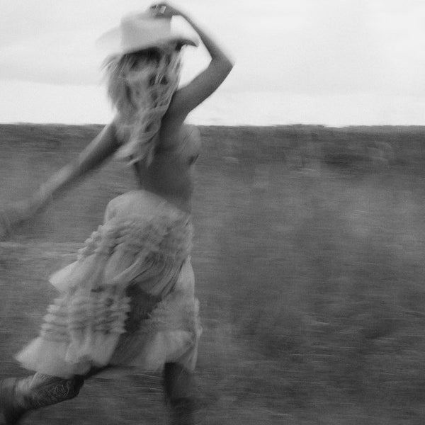 Person in a dress and hat running in an open field