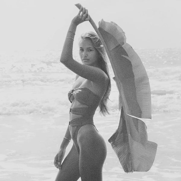 Black and white photo of a person holding a surfboard on a beach