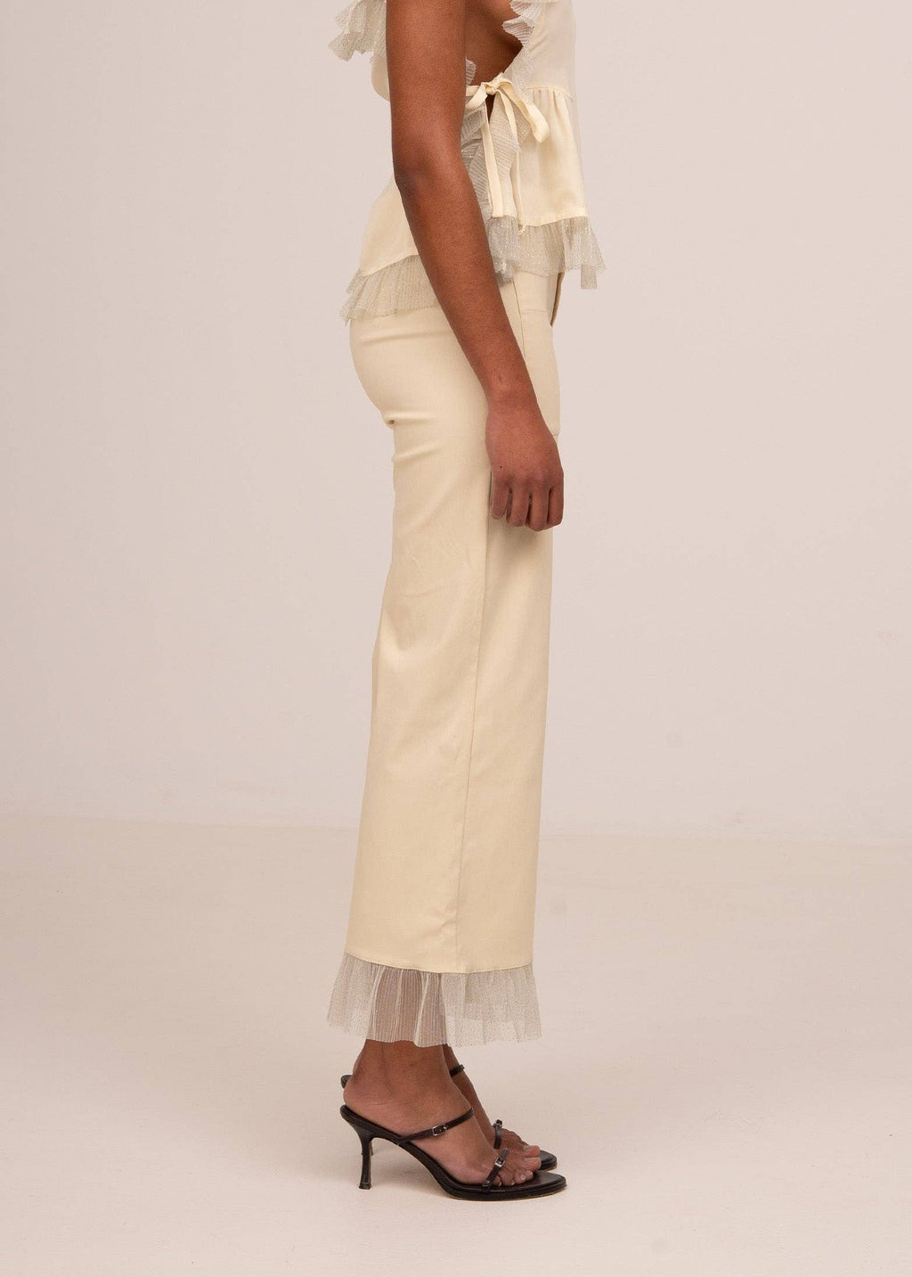 Beige pants with lace trim worn by a person on a plain background