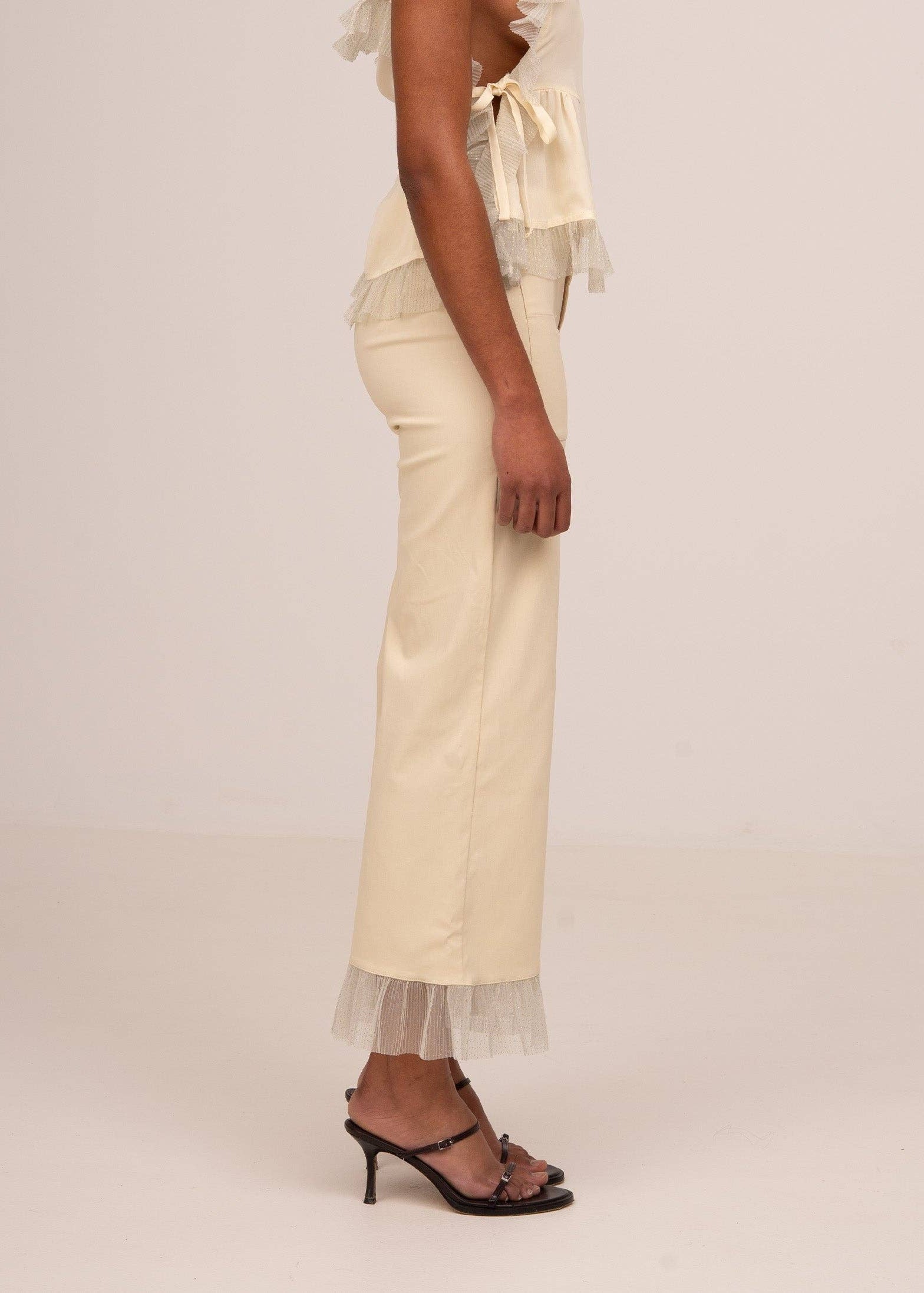 Beige pants with lace trim worn by a person on a plain background