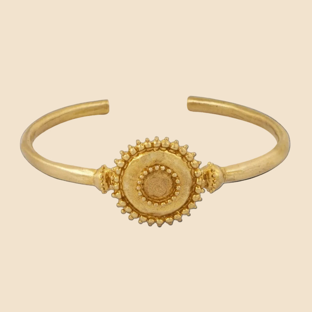 Gold bracelet with a circular design on a white background