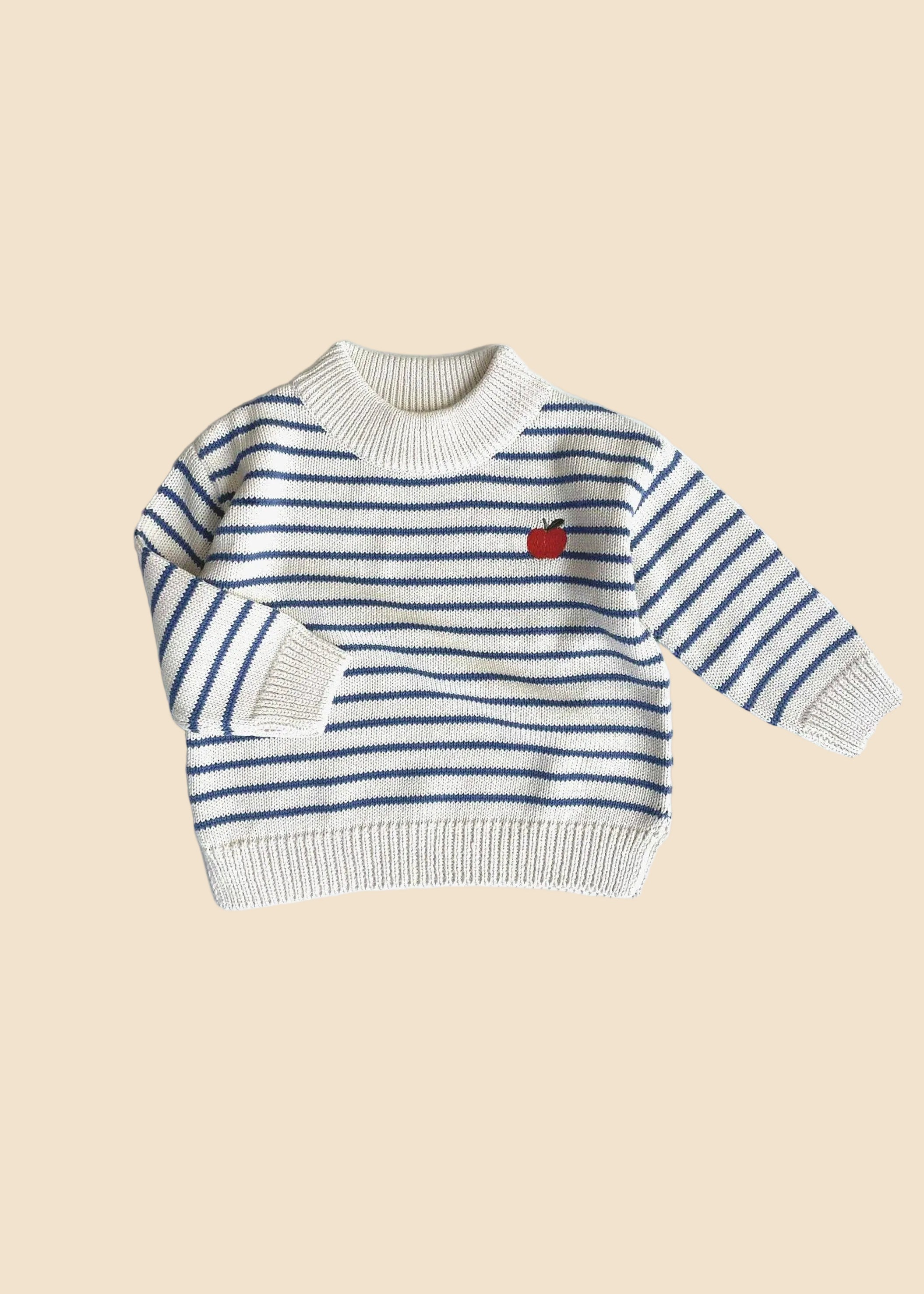 Striped sweater with a red apple design on a white background