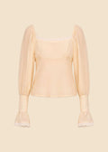 Light yellow blouse with sheer sleeves on a beige background