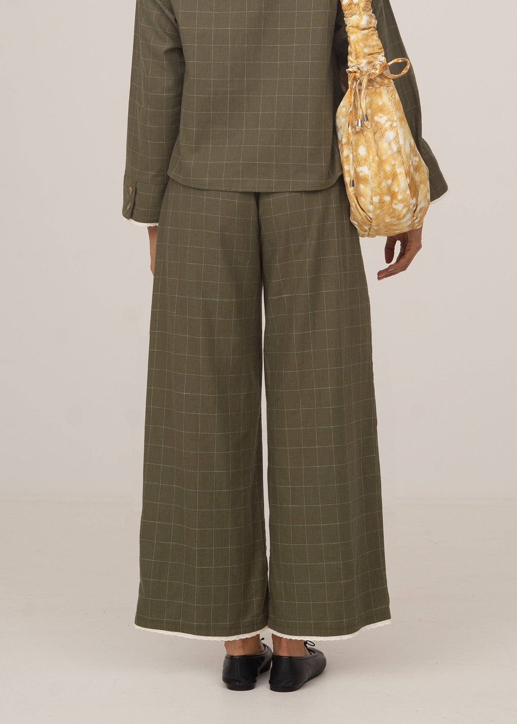 Person wearing a green checkered suit with wide-leg pants on a plain background