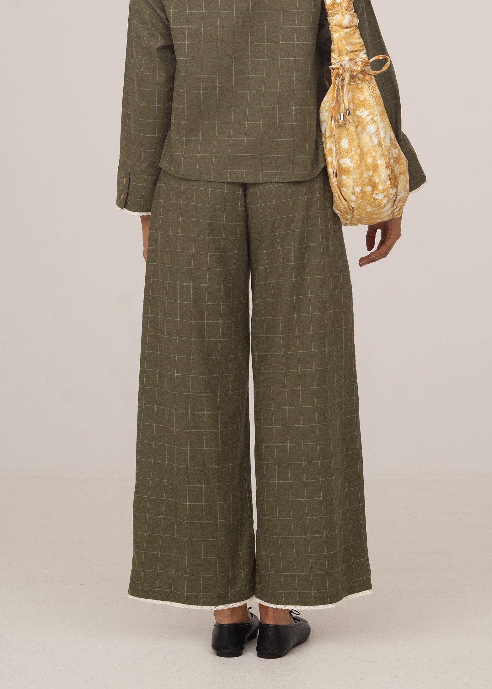 Person wearing a green checkered suit with wide-leg pants on a plain background