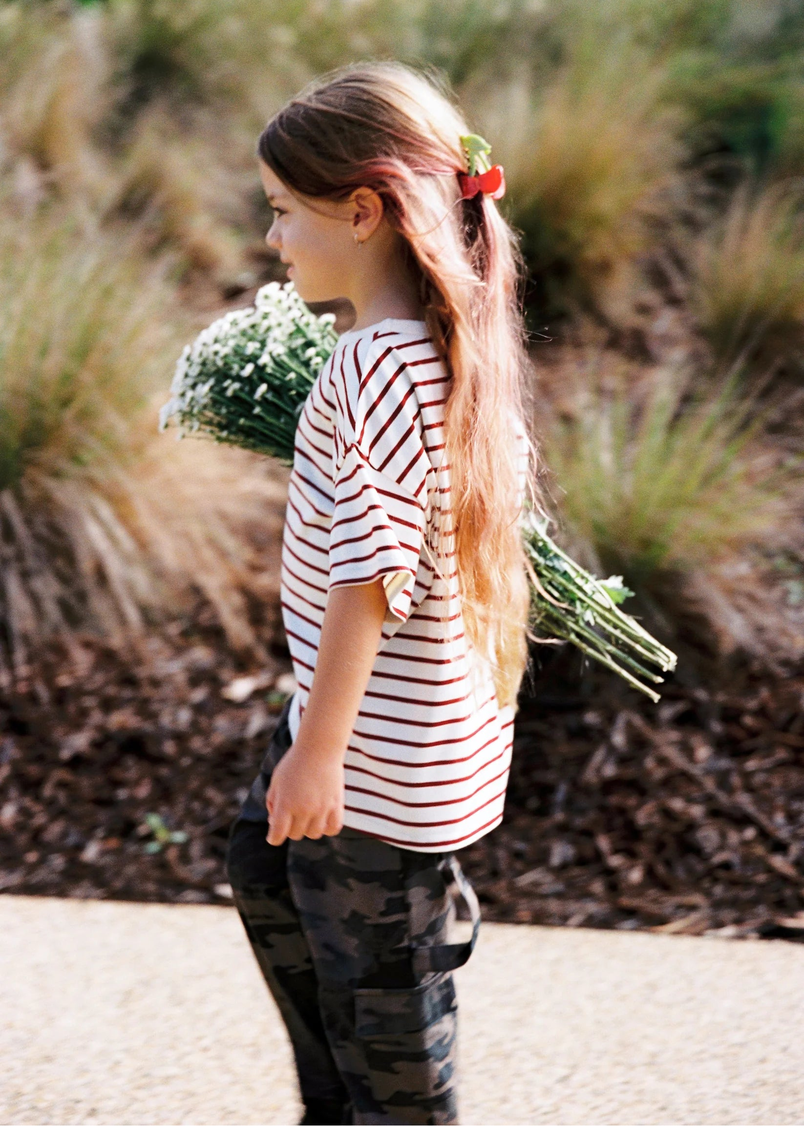 Young girl in a striped shirt holding flowers outdoors