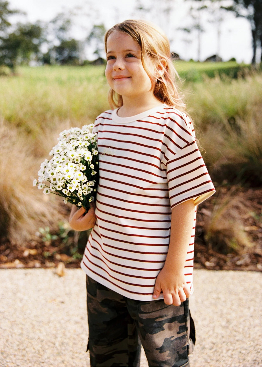 Child holding flowers outdoors with a natural background