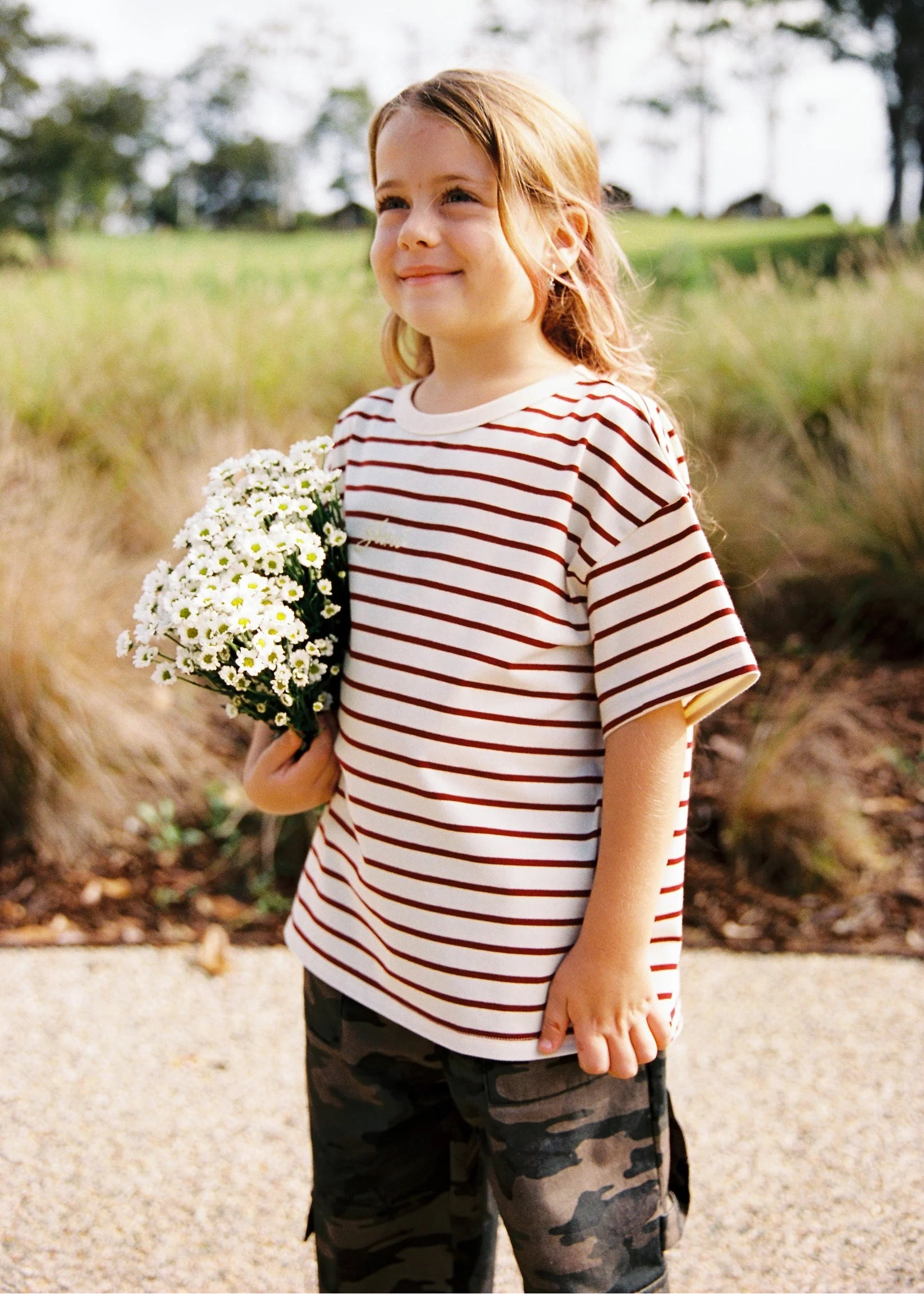 Child holding flowers outdoors with a natural background