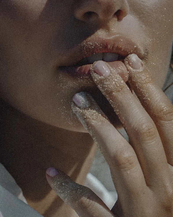 Close-up of a person with glittery makeup on their lips and fingers.